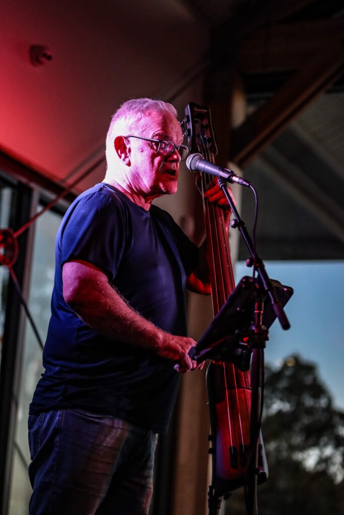 Bob Connor signing into a mic and playing electric stand up fretless bass taken at Live at the Wharf in Ulverstone Tasmania